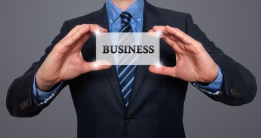 Businessman holds white card with Business sign. Isolated on various backgrounds ( grey, blue, office, white) - Stock Image