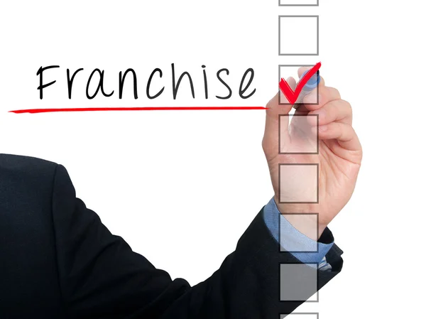 Businessman hand writing Franchise and check listing task. Isolated on blue background. Stock photo — Stock fotografie