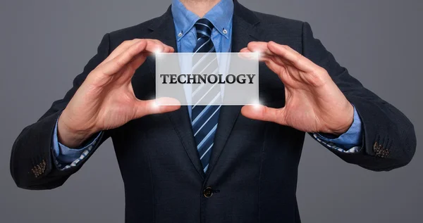 Businessman holds white card with Technology sign, Grey - Stock Photo — ストック写真