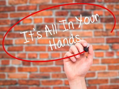 Man Hand writing It's All In Your Hands  with black marker on vi