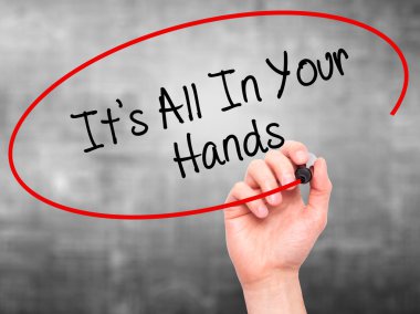 Man Hand writing It's All In Your Hands  with black marker on vi