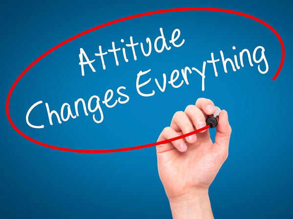 Человек, пишущий "Отношение меняет все" черным маркером
