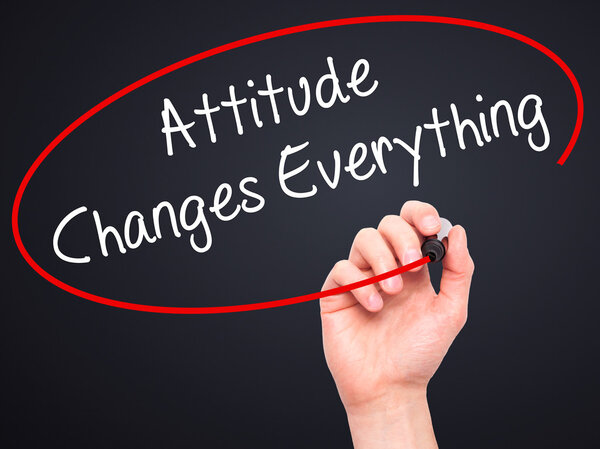 Человек, пишущий "Отношение меняет все" черным маркером
