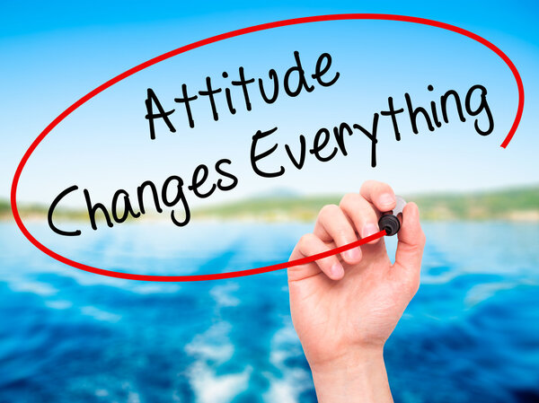 Человек, пишущий "Отношение меняет все" черным маркером
