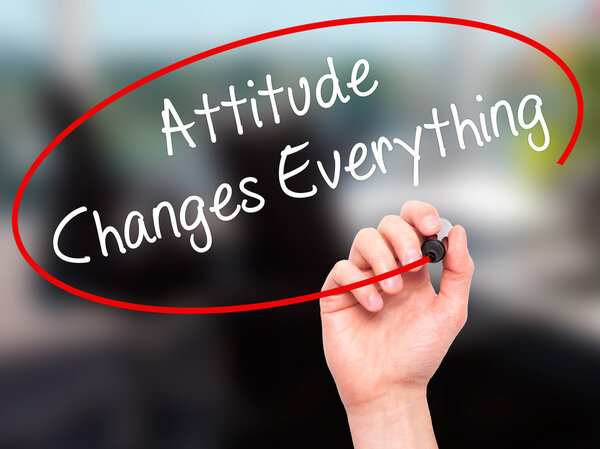 Человек, пишущий "Отношение меняет все" черным маркером
