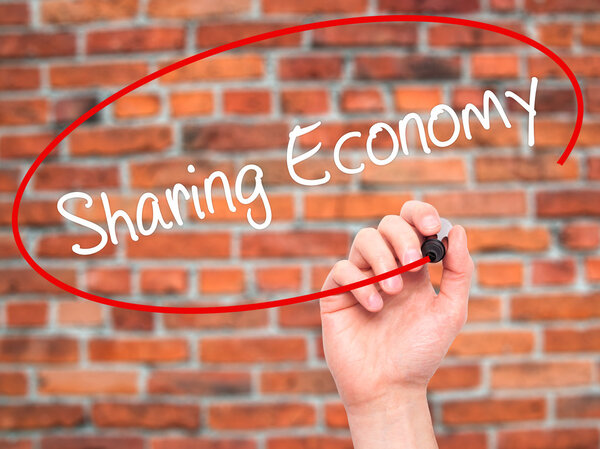 Man Hand writing Sharing Economy with black marker on visual scr