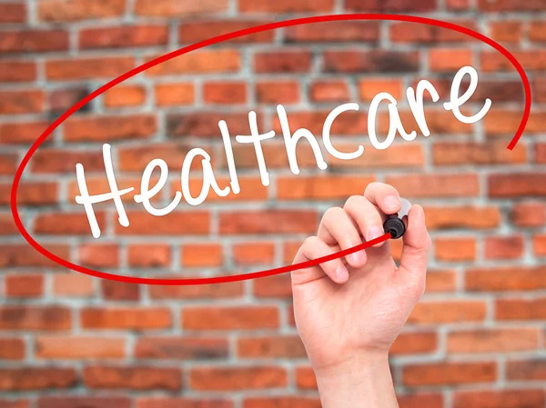 Man Hand writing Healthcare with black marker on visual screen — Stock Photo, Image