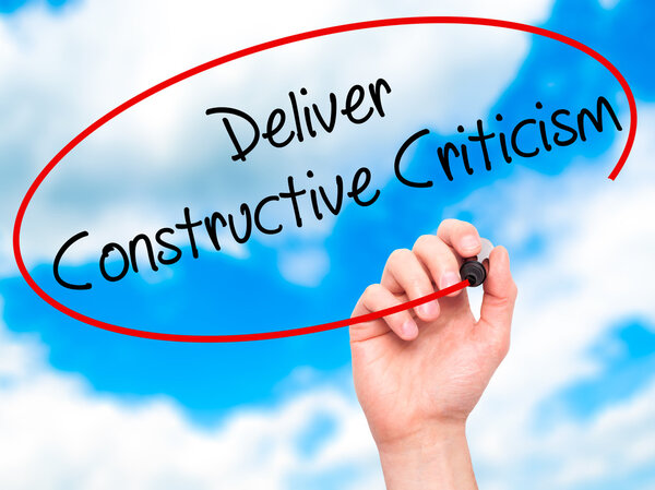 Man Hand writing Deliver Constructive Criticism with black marke