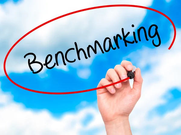 Mann schreibt Benchmarking mit schwarzem Marker auf visuellem Geröll — Stockfoto