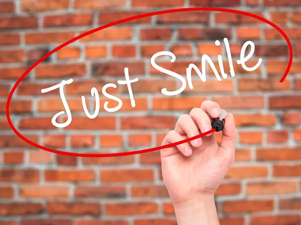 Человек, пишущий Just Smile с черным маркером на экране — стоковое фото