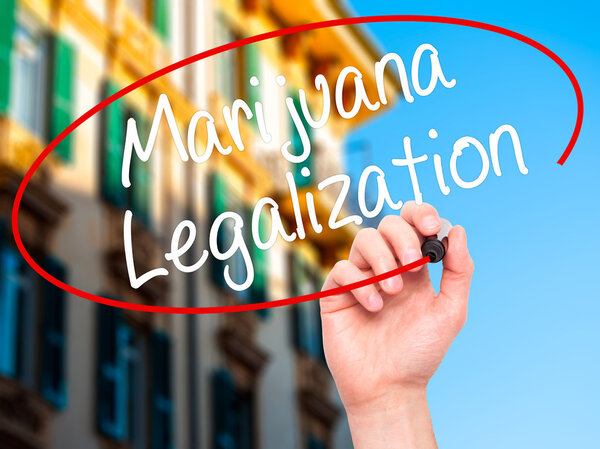 Мужская рука пишет легализацию марихуаны с черным маркером на висе
