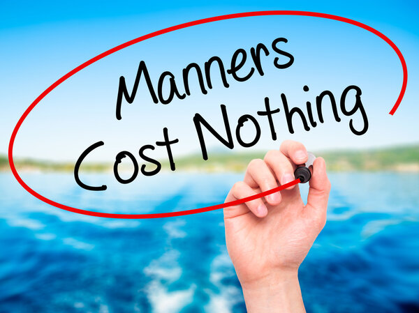Man Hand writing Manners Cost Nothing with black marker on visua