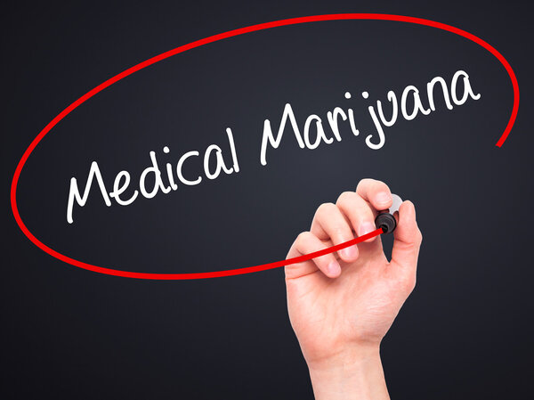 Мужская рука пишет медицинскую марихуану с черным маркером на картинке
 