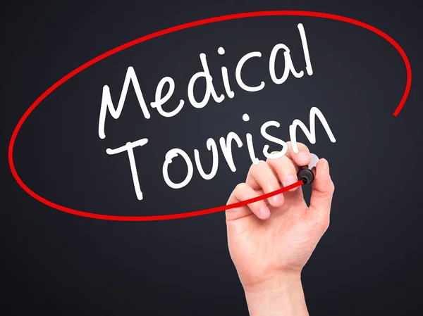 Man Hand writing Medical Tourism with black marker on visual scr — Stock Photo, Image