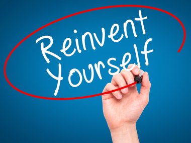 Man Hand writing Reinvent Yourself with black marker on visual s