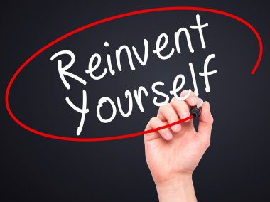 Man Hand writing Reinvent Yourself with black marker on visual s