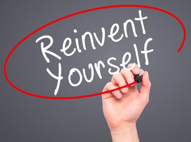 Man Hand writing Reinvent Yourself with black marker on visual s