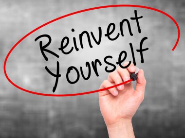 Man Hand writing Reinvent Yourself with black marker on visual s