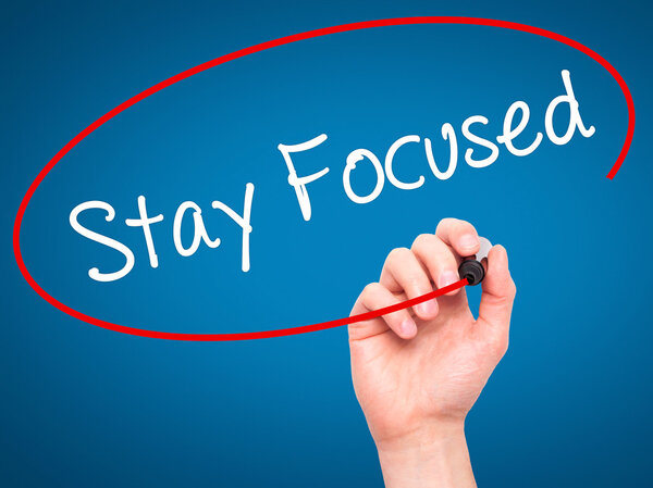 Man Hand writing Stay Focused with black marker on visual screen