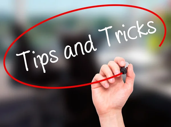 Man Hand writing Tips and Tricks with black marker on visual scr — Stock Photo, Image