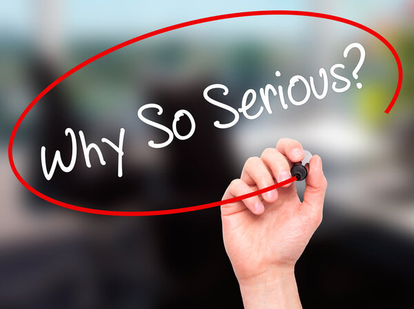 Мужская рука пишет "Почему так серьезно?" с черным маркером на визуальном скрабе
