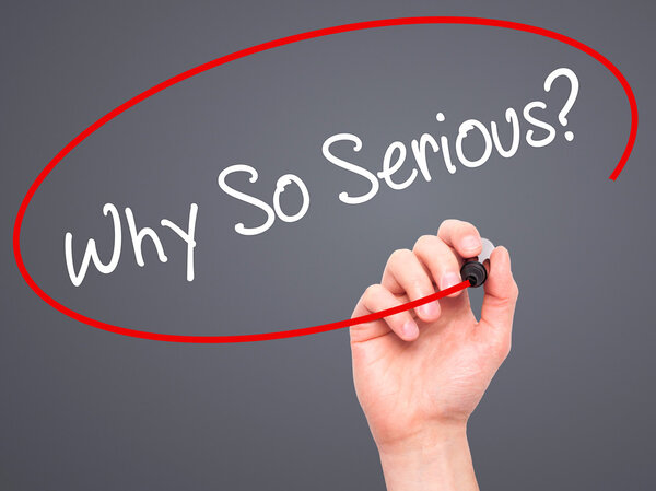 Мужская рука пишет "Почему так серьезно?" с черным маркером на визуальном скрабе
