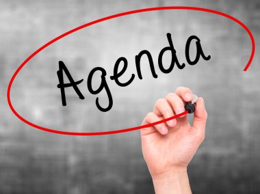 Man Hand writing Agenda with marker on transparent wipe board