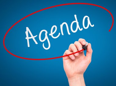 Man Hand writing Agenda with marker on transparent wipe board