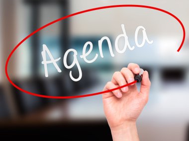 Man Hand writing Agenda with marker on transparent wipe board