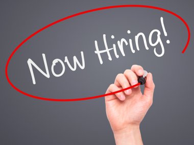 Man Hand writing Now Hiring! with marker on transparent wipe boa