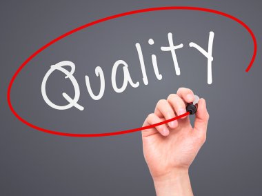 Man Hand writing Quality with marker on transparent wipe board