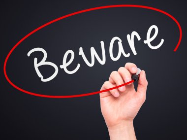 Man Hand writing Beware  with marker on transparent wipe board