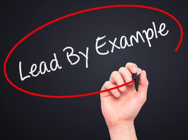 Man Hand writing Lead By Example with marker on transparent wipe