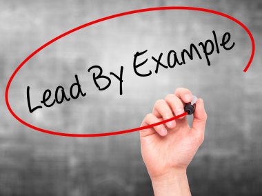 Man Hand writing Lead By Example with marker on transparent wipe