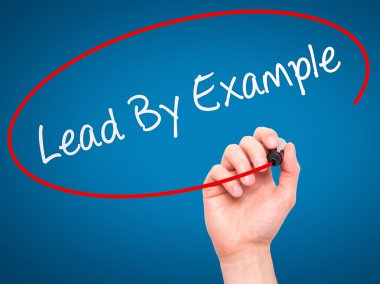 Man Hand writing Lead By Example with marker on transparent wipe