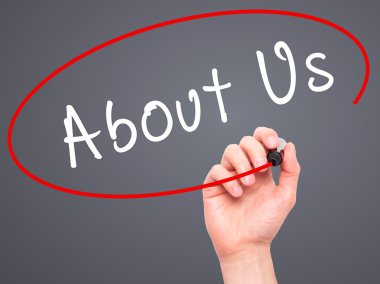 Man Hand writing About Us with marker on transparent wipe board