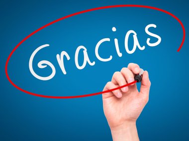 Man Hand writing Gracias with marker on transparent wipe board