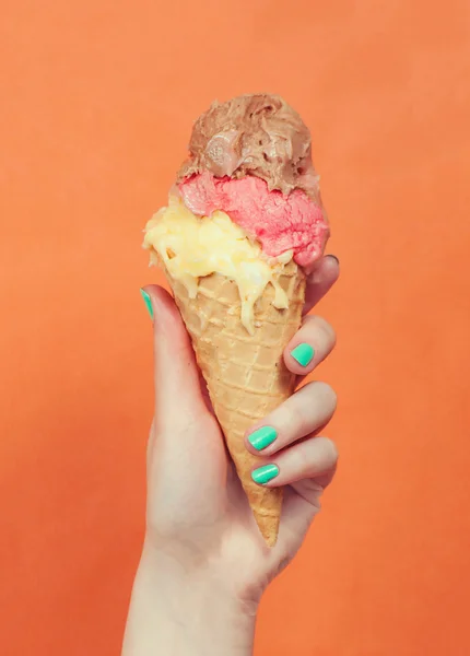 Mulher mão segurando sorvete no fundo laranja — Fotografia de Stock