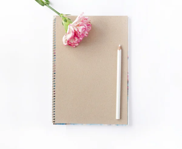 Блокнот и цветок с белым карандашом на белом фоне с мотивационным текстом — стоковое фото
