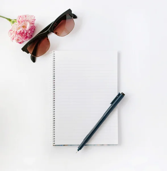 Flor e óculos de sol com bloco de notas e caneta — Fotografia de Stock