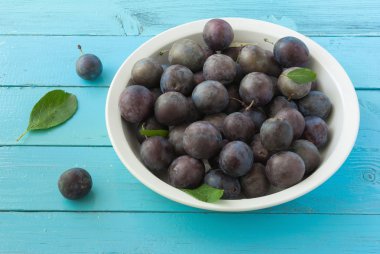 Mavi ahşap zemin üzerine kase taze olgun Erik