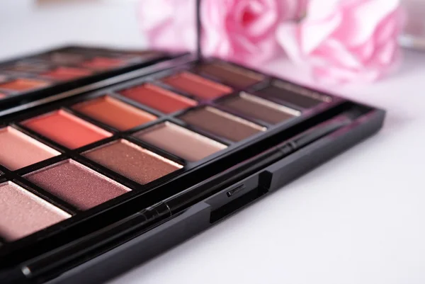 Lidschatten-Make-up-Palette in Nahaufnahme mit Rosen auf dem Hintergrund — Stockfoto