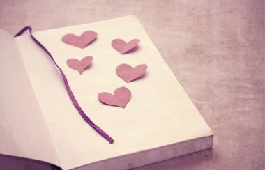 Paper hearts on a book clipart