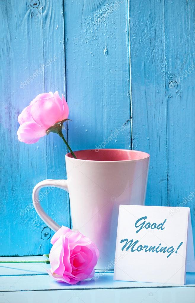 Mug with pink roses on blue wood background with good morning text