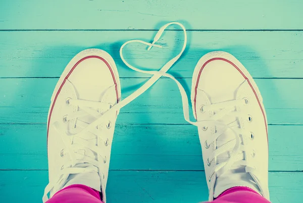 Zapatillas blancas con corazón sobre fondo de madera azul, imagen filtrada —  Fotos de Stock