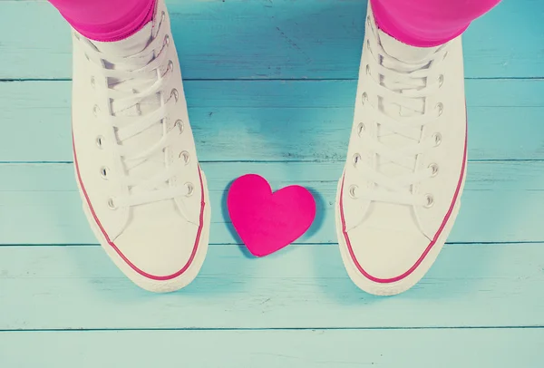 Zapatillas blancas con corazón sobre fondo de madera azul, imagen filtrada — Foto de Stock