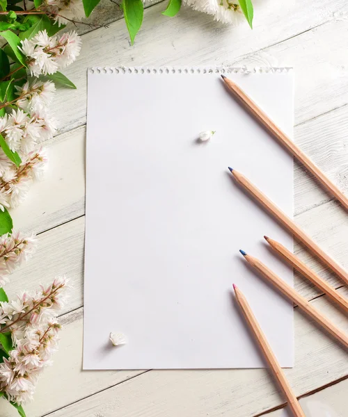 Papper med blommor och pennor på vit trä bakgrund — Stockfoto