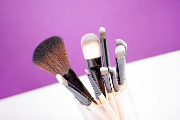 Pinceles de maquillaje de cerca sobre fondo púrpura —  Fotos de Stock