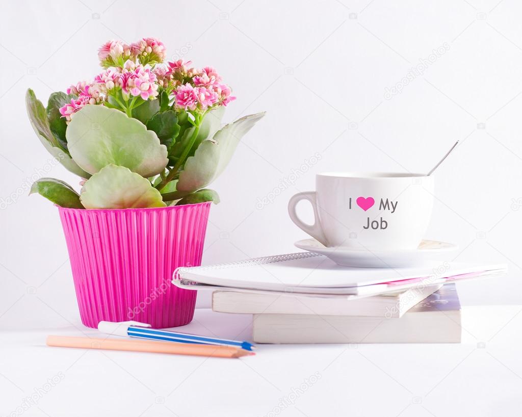 Workplace with flower books and a coffee cup with text 'I love my job