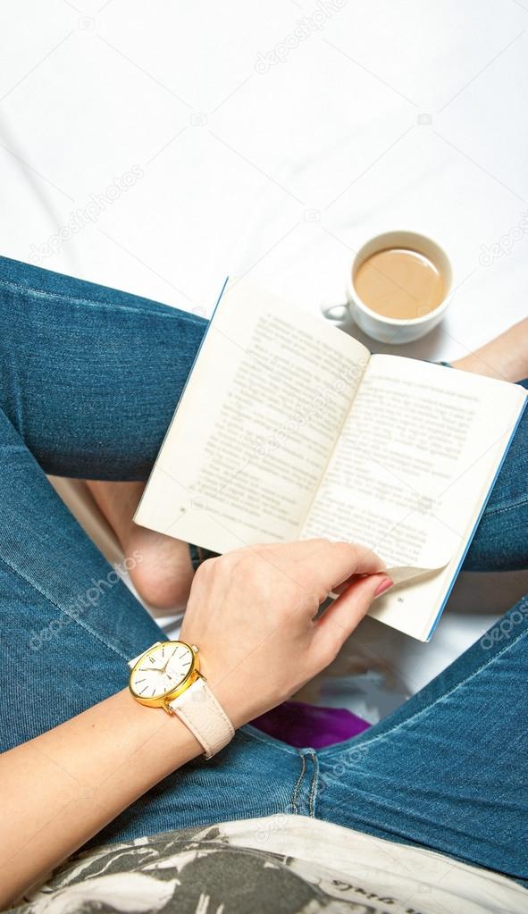 Woman sitting with book in hands and cup of coffee